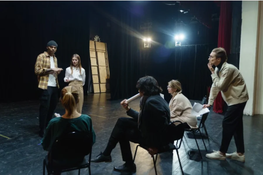 Actors on stage rehearsing and discussing a scene.
